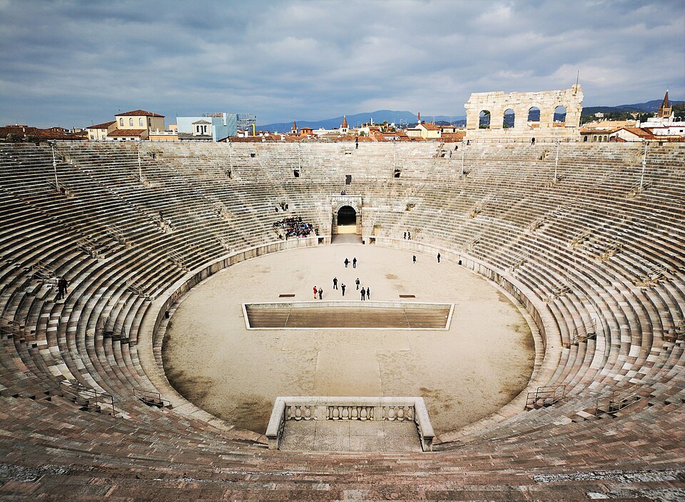 The whole oval bowl from the upper tiers, the city's roofs beyond