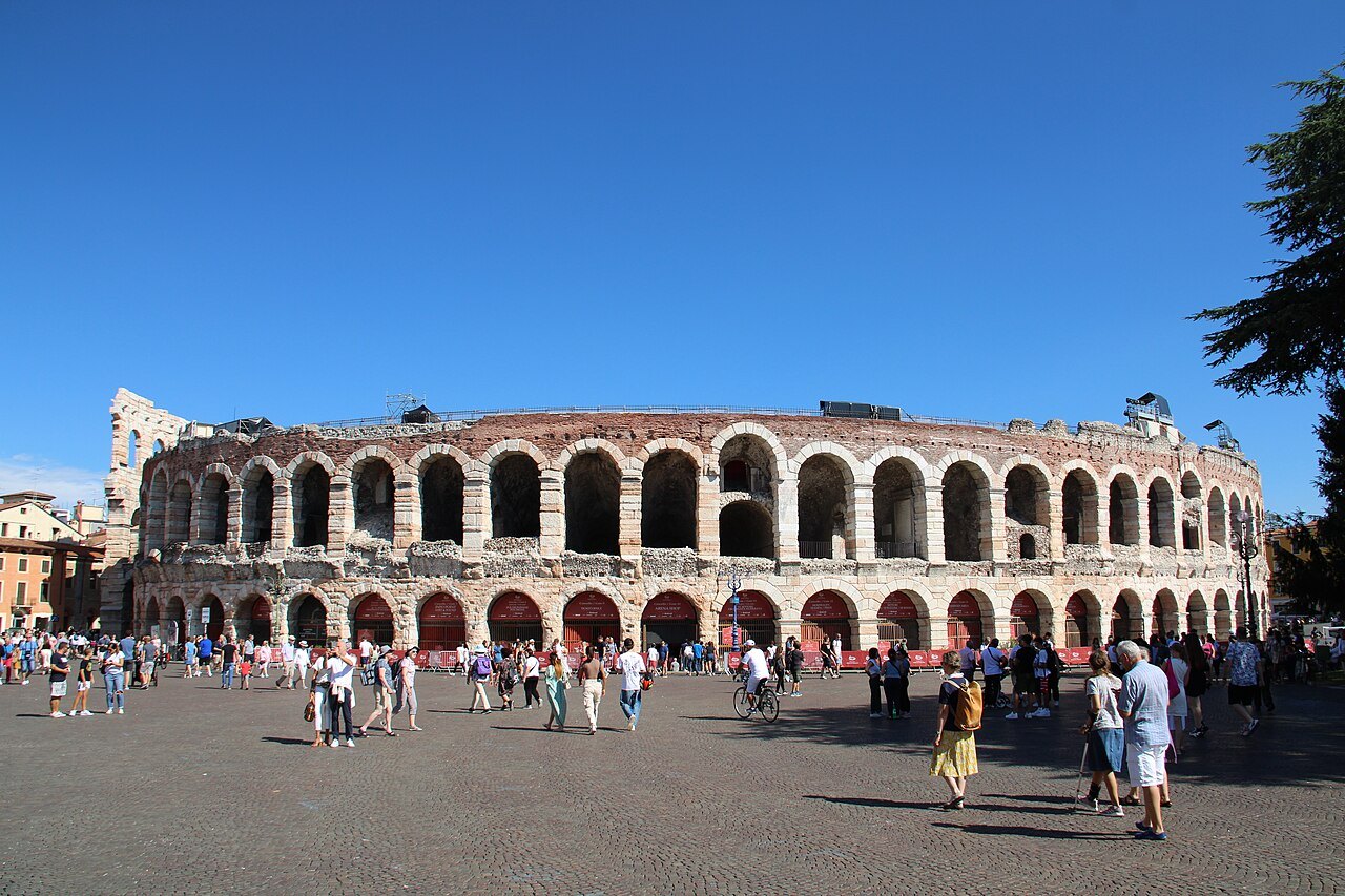 The Arena's full curve of arches on Piazza Bra under a blue sky