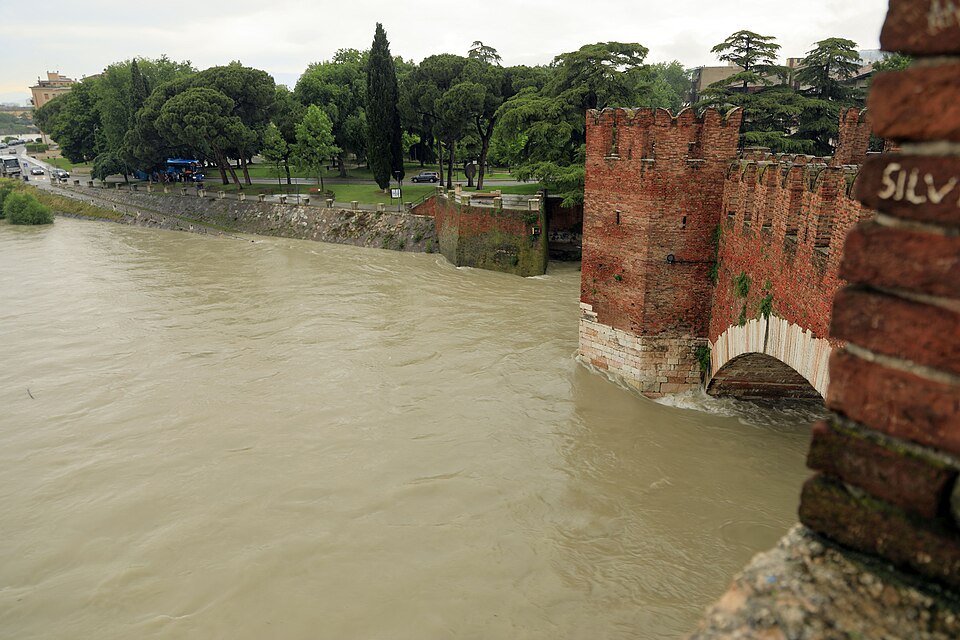 The brick piers of the Ponte Scaligero in the brown water of a high Adige