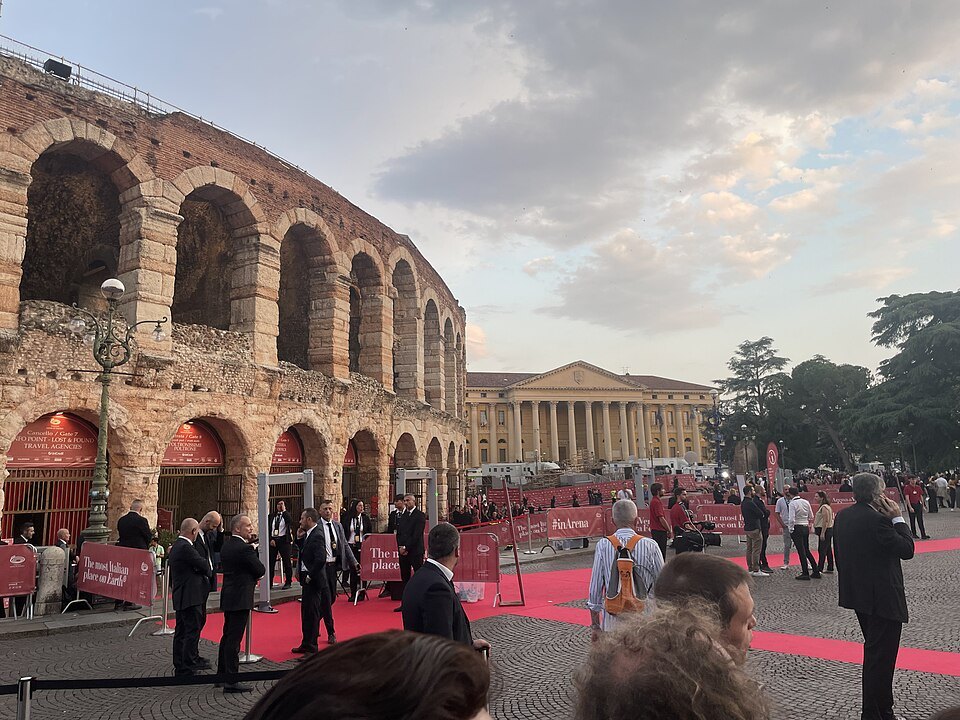 Opera-goers on a red carpet outside the Arena at dusk