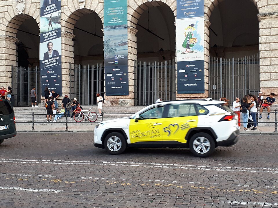 A white taxi crossing the paving in front of the Gran Guardia