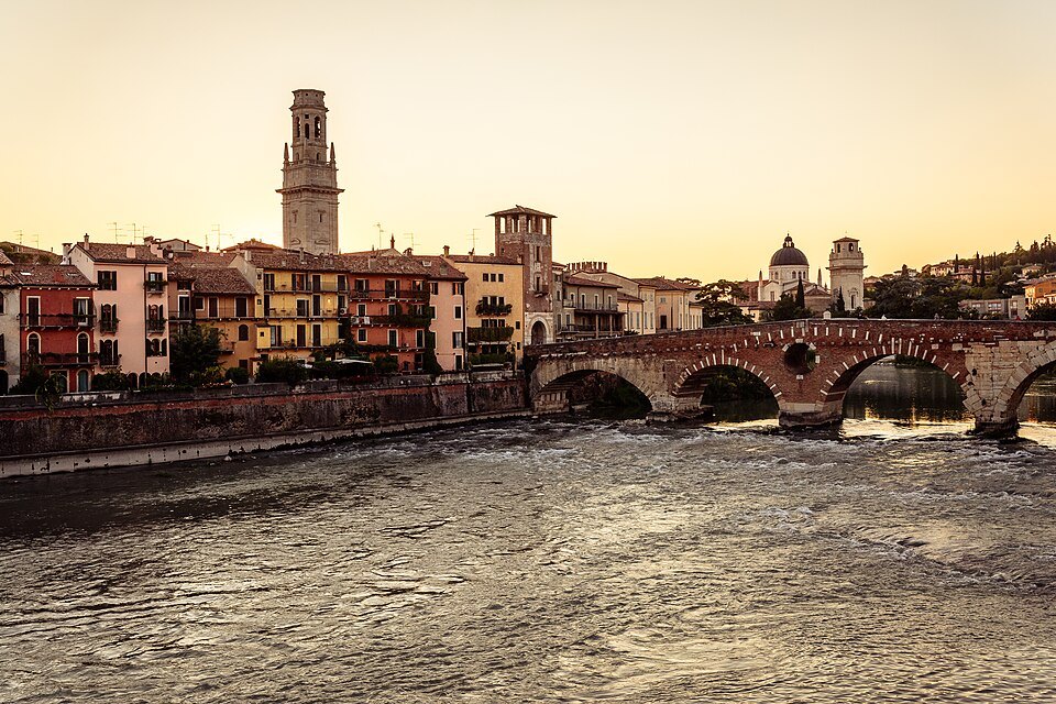 The Duomo's bell tower above the river and the Ponte Pietra at sunset
