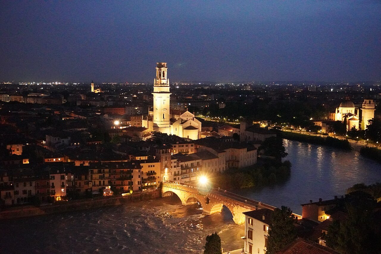 Verona at night from the hill: the Duomo's bell tower, the lit Adige and the bridges
