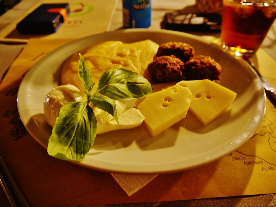 A dinner plate of polenta, meatballs, cheese and basil