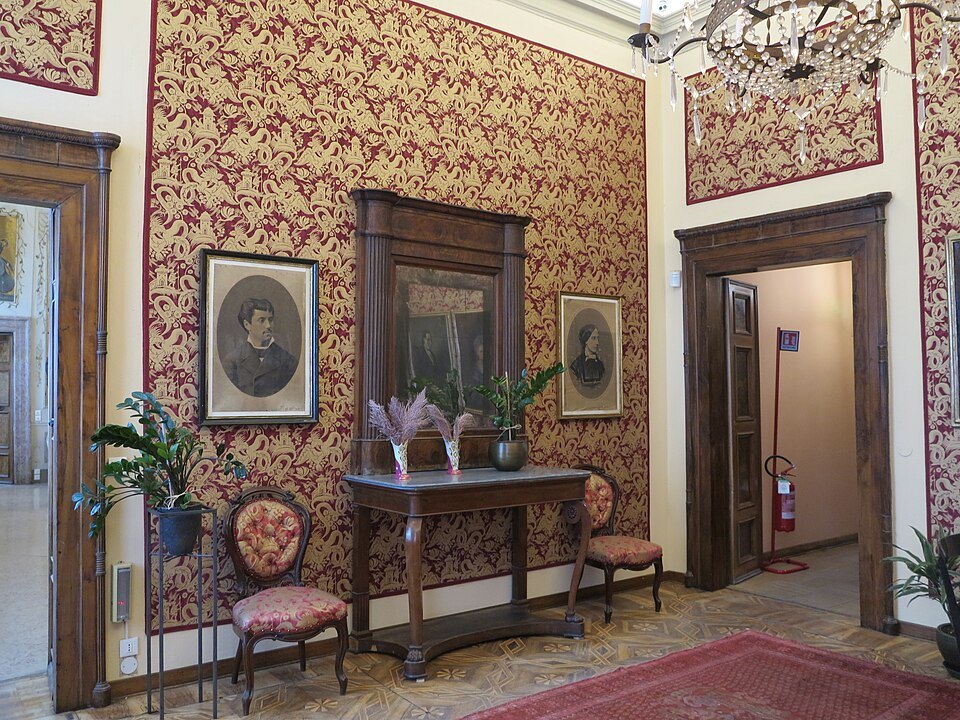Framed photographs on the damask wall of a palace room