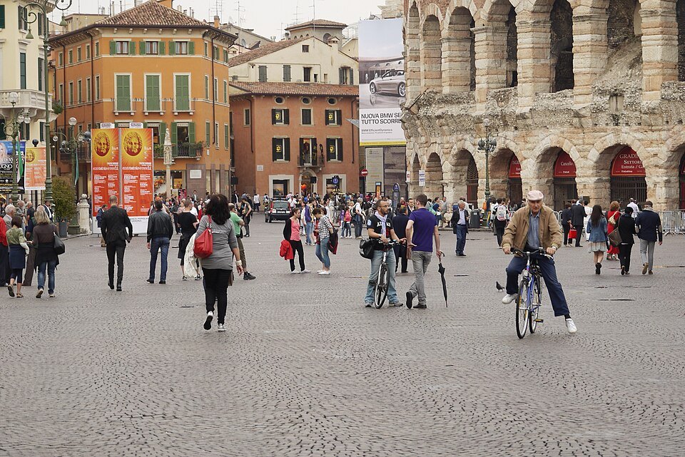 Crowds crossing the Liston's paving, the Arena's arches at the right