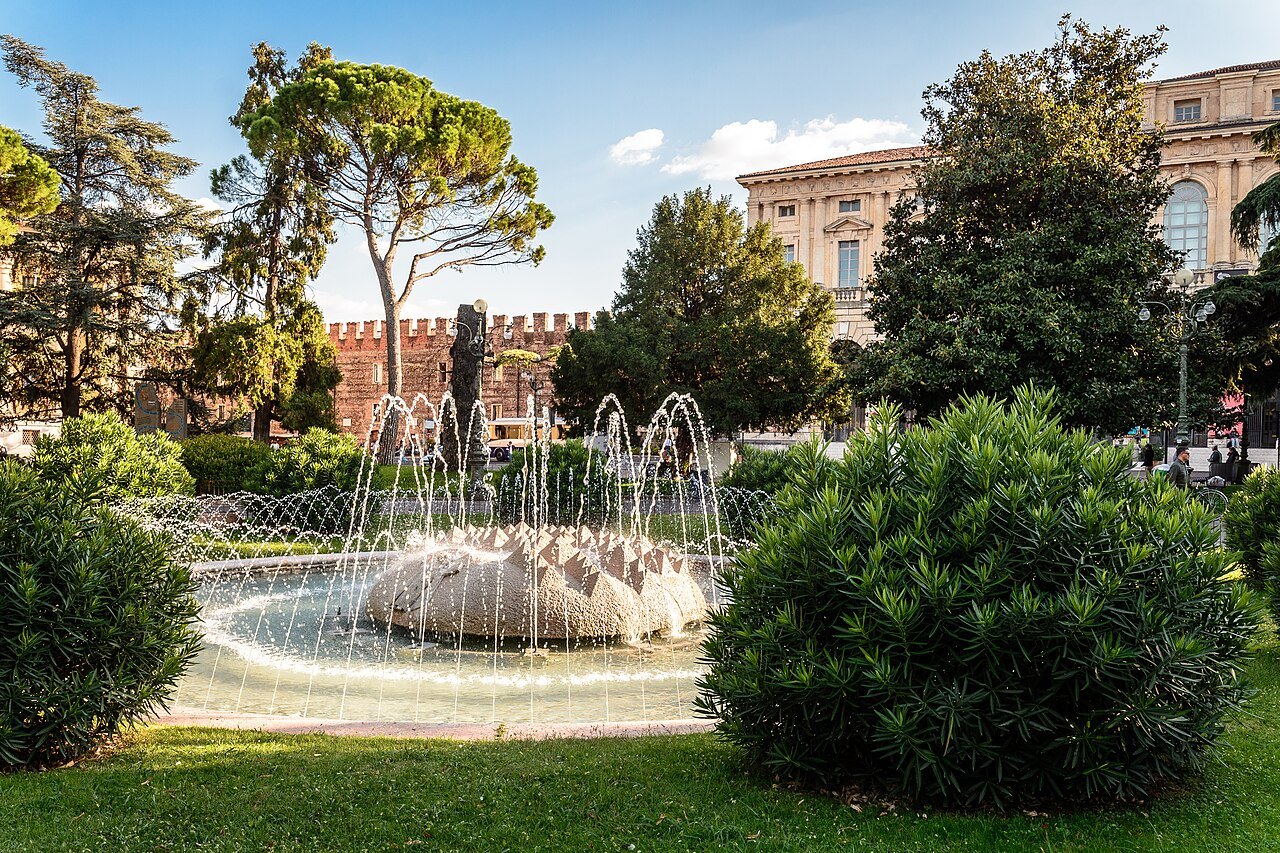 The fountain in the gardens of Piazza Bra, trees and palazzi behind