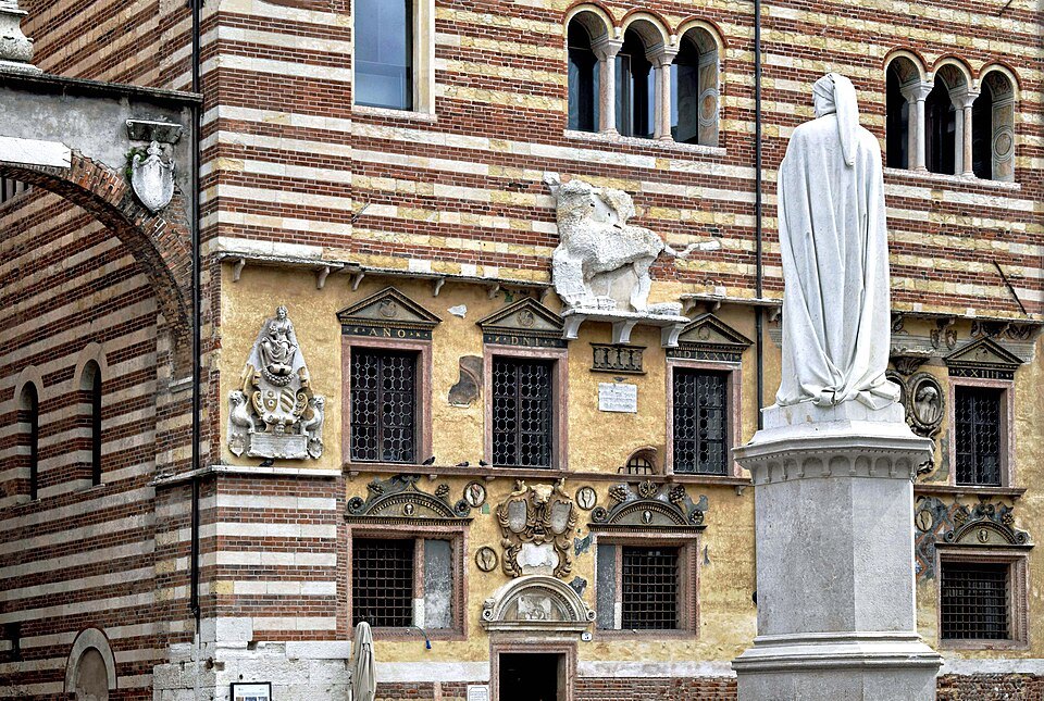 Dante in marble, with the striped front of the Palazzo della Ragione behind