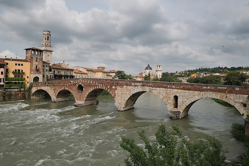 The Ponte Pietra and the Duomo tower under a cloudy sky