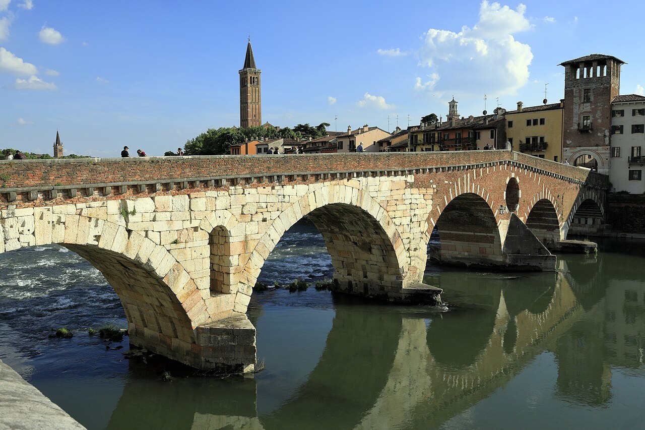 The Ponte Pietra's pale stone and brick arches, with the Duomo's bell tower behind