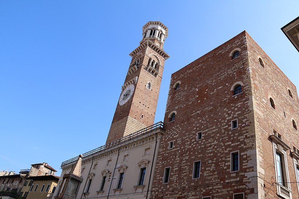 The tower's stripes of brick and stone over the palazzo roofs
